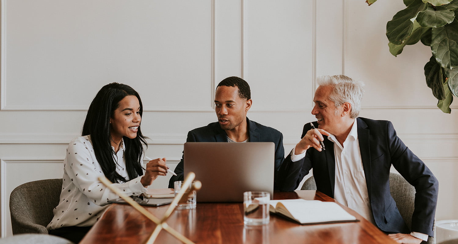 3 people discussing work together in a meeting room
