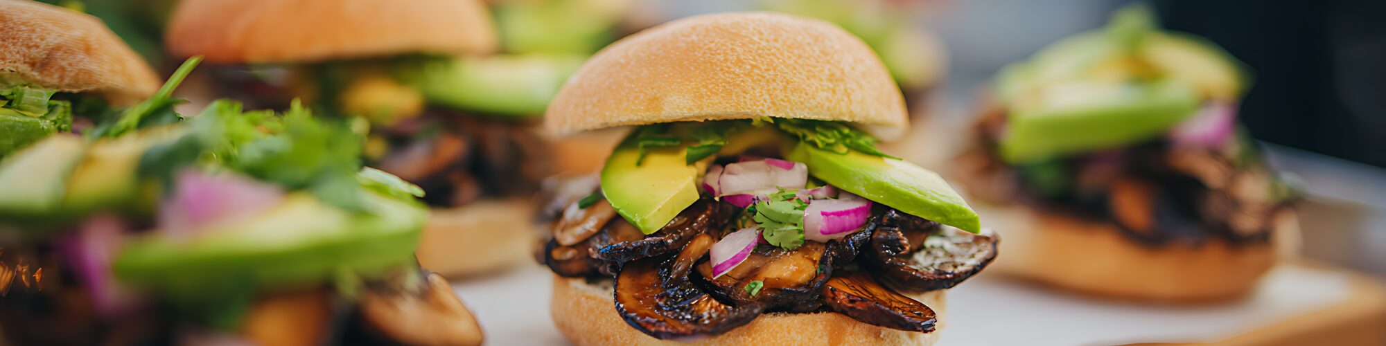 Vegan burgers made with mushrooms laid in threes on a counter top.