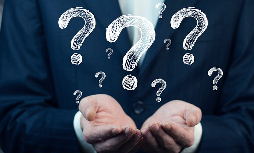 Man in a suit with his hands raised with illustrated questions marks above.