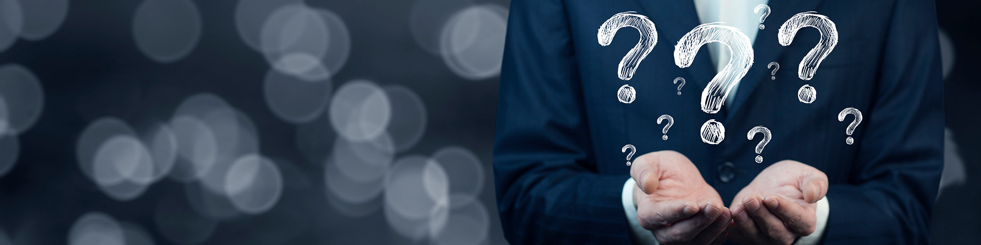 Man in a suit with his hands raised with illustrated questions marks above.