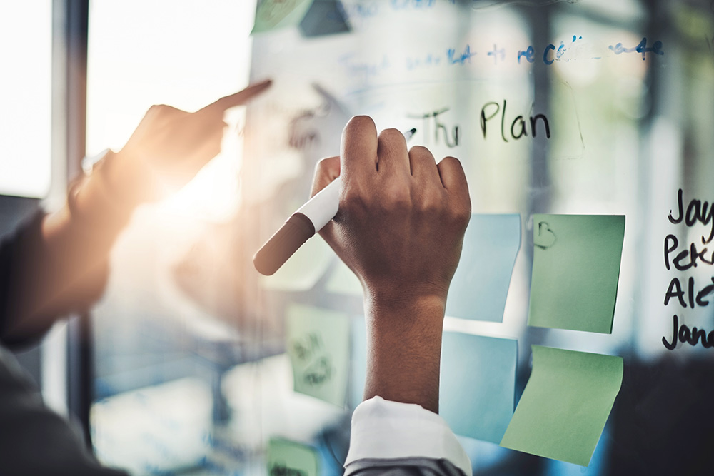 Writing the plan on a transparent whiteboard.