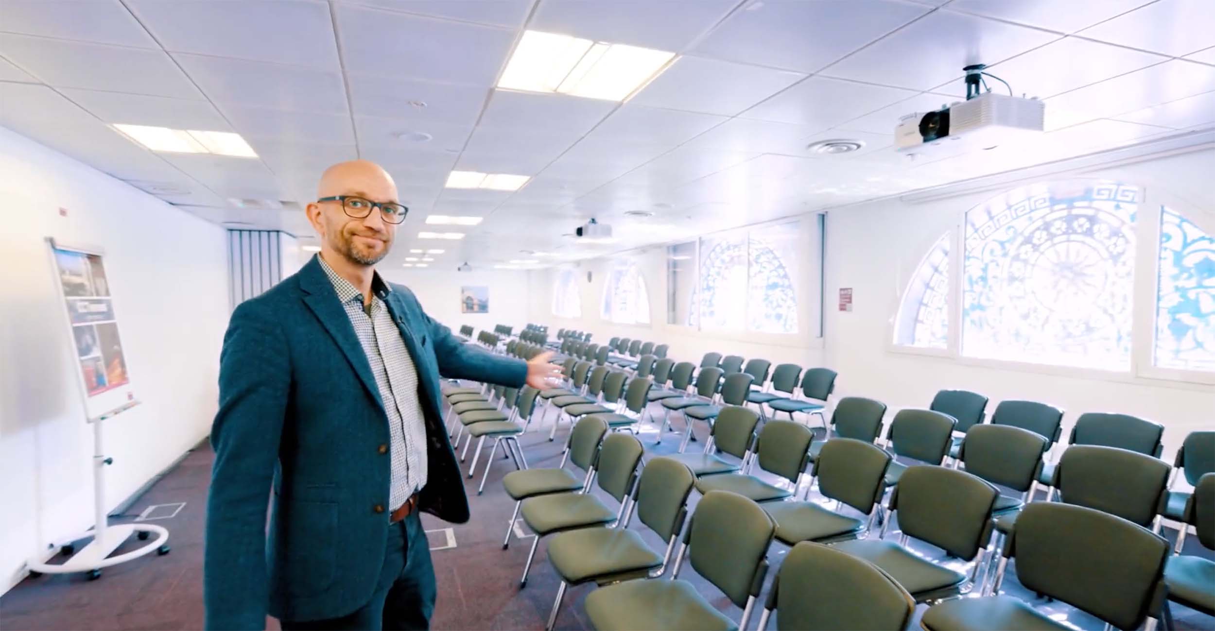 Man in suit with arm out at seats.